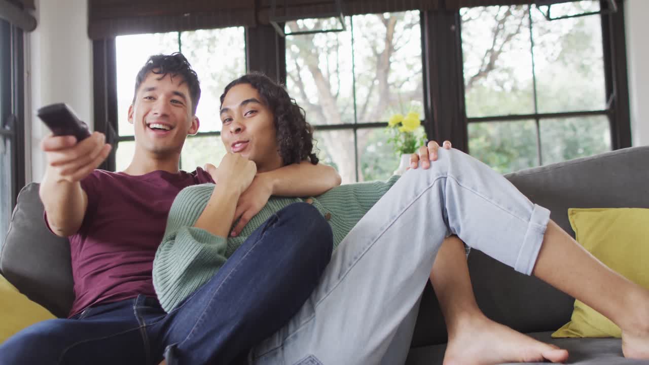 소파에 앉아서 기 ⁇ 하고 거실에서 tv를 보는 다양한 남성 커플