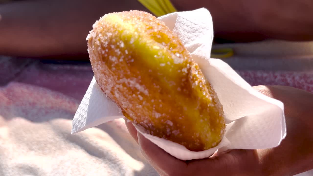 빛 아래 해변에서 휴식을 취하는 동안 설탕으로 인 신선한 도을 들고있는 사람. 활기찬 분위기는 바가에서 느한 휴가의 본질을 포착합니다.