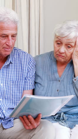 worried senior couple looking at document