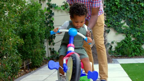 front view of young black father and little son playing in back yard of their home 4k