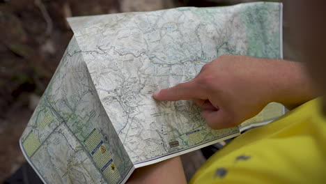 Hiker-looking-and-pointing-at-map-close-up