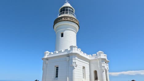 tourists exploring a white lighthouse by the sea