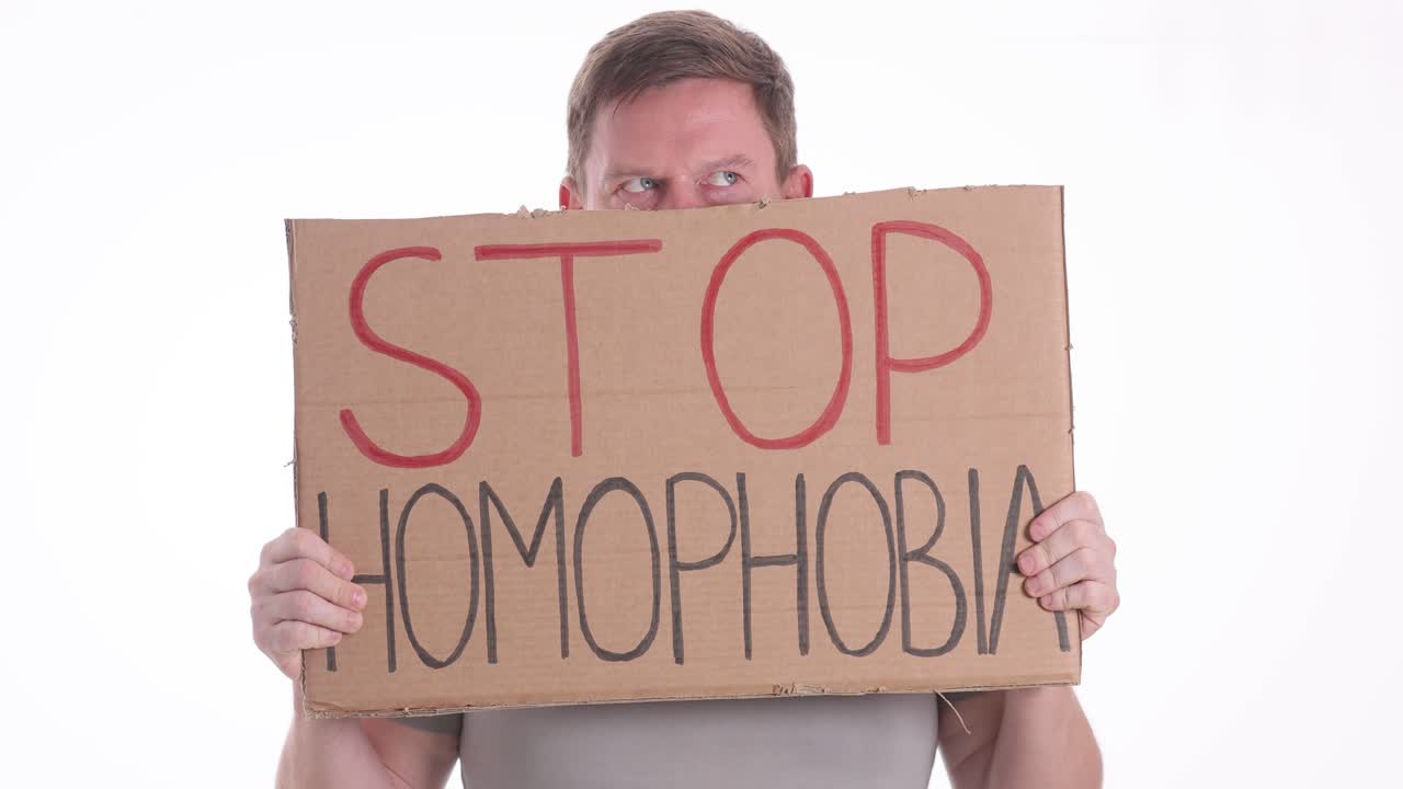 Man holding a 'STOP HOMOPHOBIA' sign