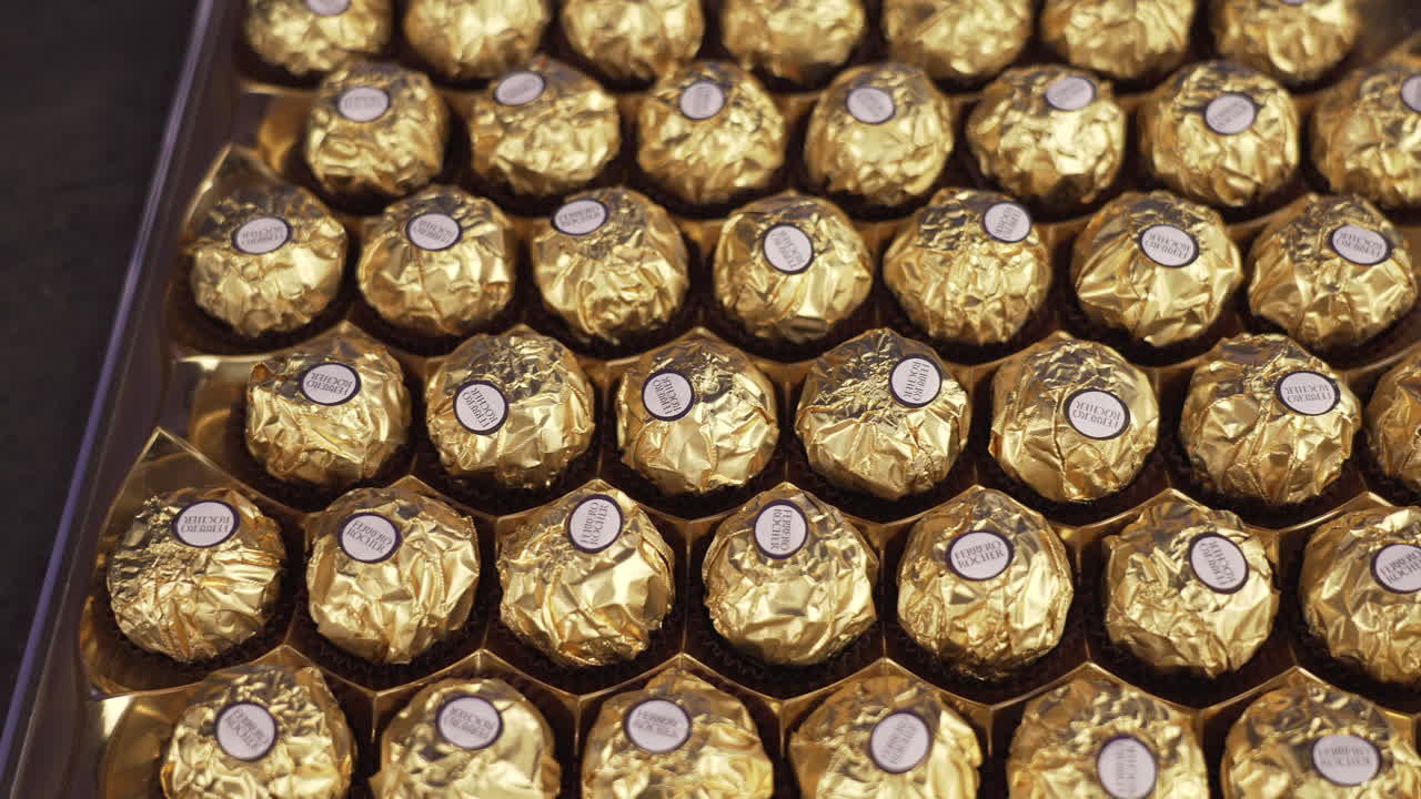 Big Ferrero Rocher box with chocolate candy balls, fancy golden packaging, famous popular sweet dessert treat, the perfect holiday gift, 4K shot