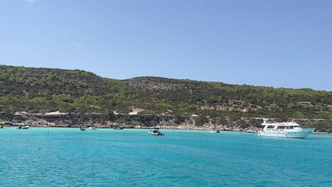 Boat-Floating-Under-The-Sun-On-The-Crystal-Clear-Water-Of-Blue-Lagoon-Beach-Near-Paphos,-Akamas-Cyprus-Island