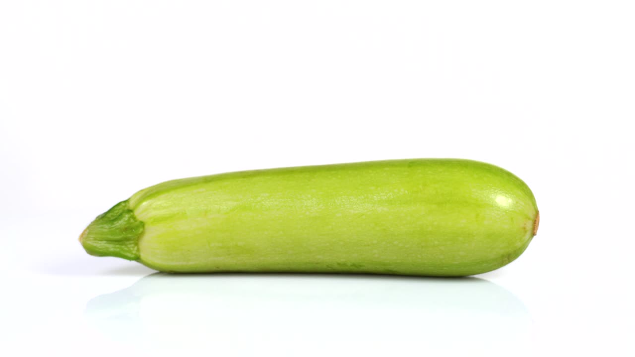 색 배경에서 회전하는 신선한 zucchini의 끝없는 루프. 측면 시각.