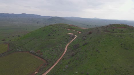 Panning-aerial-view-of-Mount-Shifon-with-winding-road-leading-to-top,-Israel