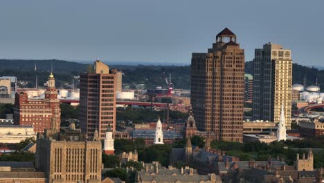 downtown of new haven lighting at sunset. aerial zoom shot. 360 state street and connecticut financial center tower in city. peaceful evening in summer. historic church towers in town