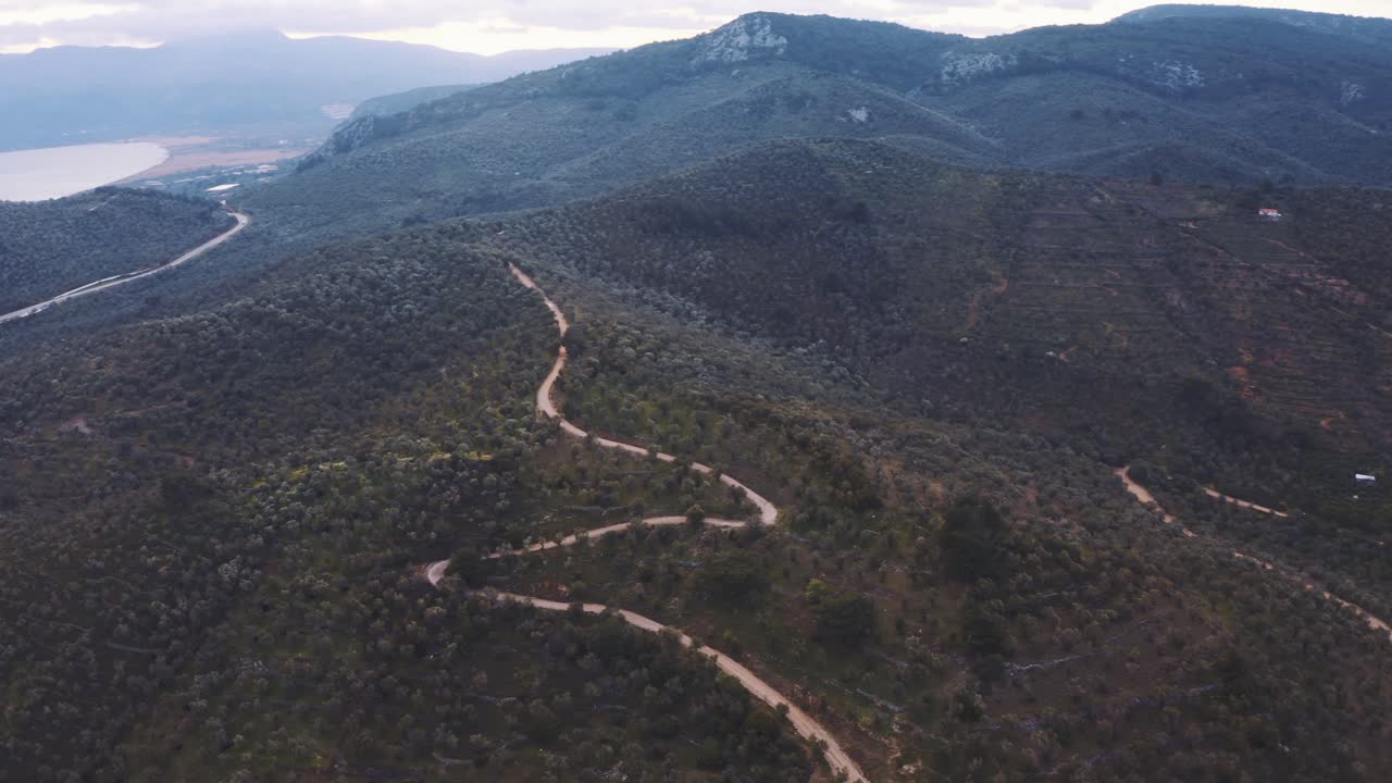 Aerial Over Winding Road In Valley With Green Hills, With Slow Pan Left. Follow Shot