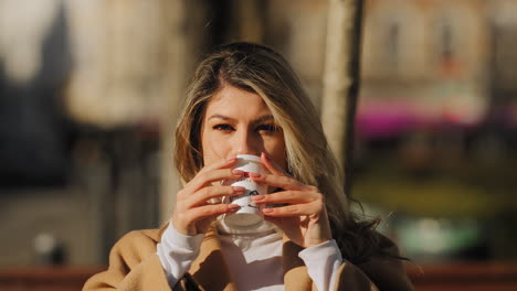 caucasian attractive blonde woman drinking coffee in slow motion looking and smiling to camera