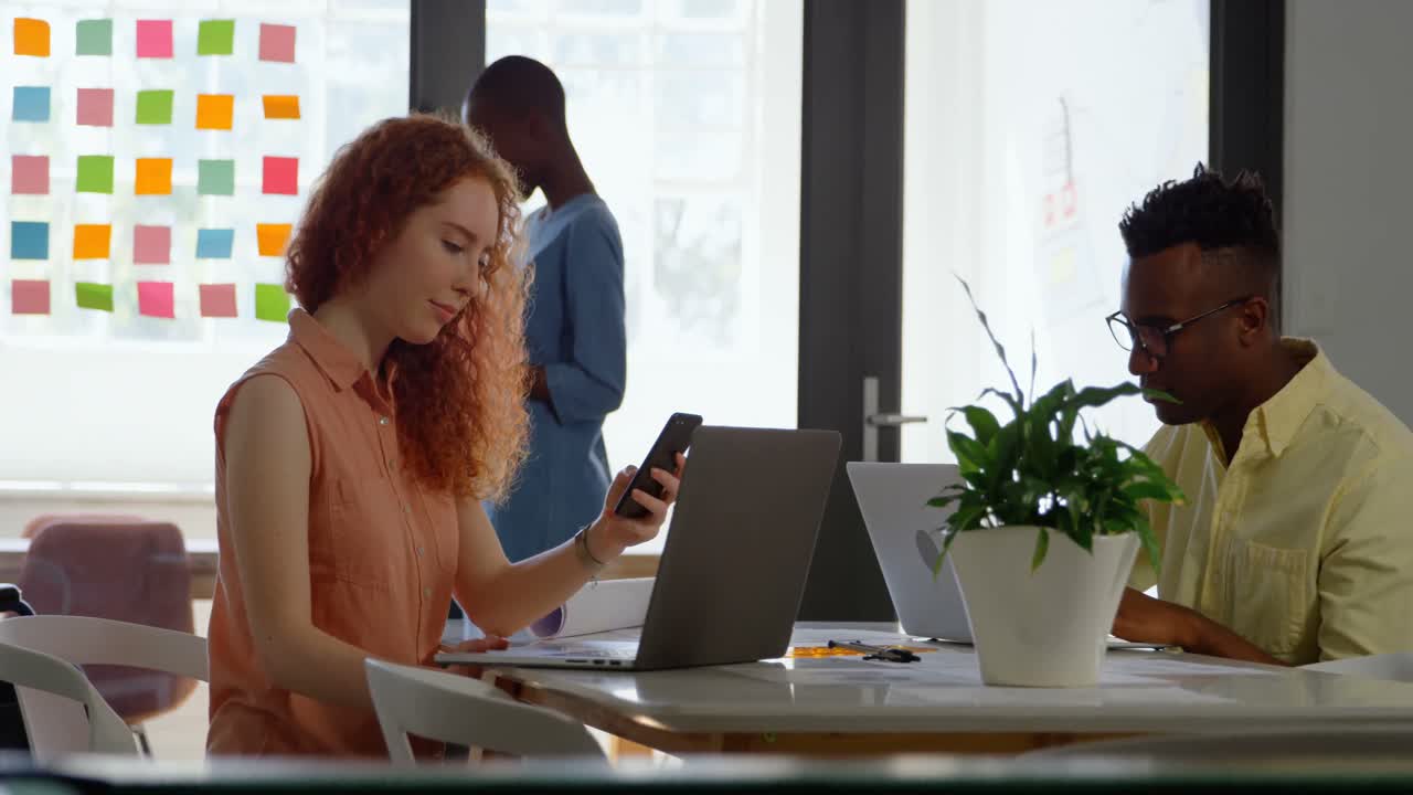 Side view of young mixed-race business team sitting at table and working in a modern office 4k