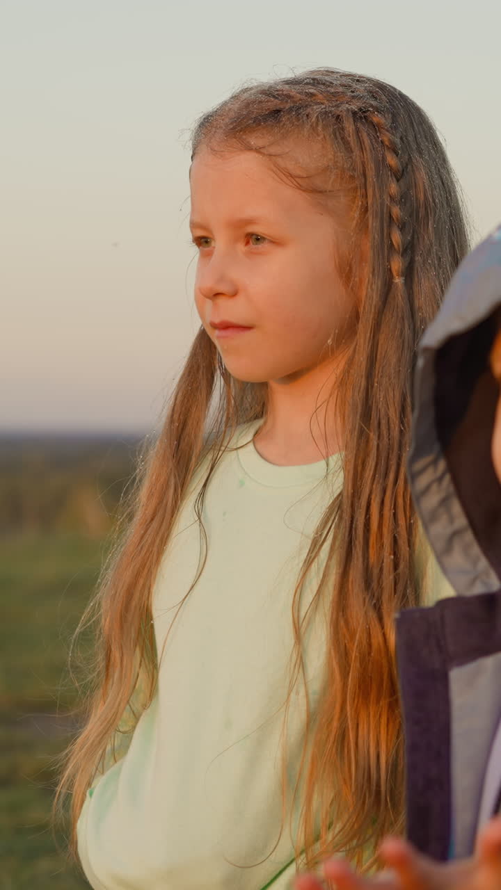 niño y niña malhumorados en la orilla del río en un clima lluvioso. niño pequeño disgustado con una niña en edad preescolar cansado de una larga caminata bajo la lluvia en el campo. estado de ánimo sombrío