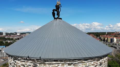 vista panorámica de las paredes de la torre de la fortaleza de piedra de skansen lejonet y la azotea con los edificios del centro de la ciudad y la comunidad en segundo plano en el día azul brillante del cielo soleado, gotemburgo, suecia, antena en ascenso
