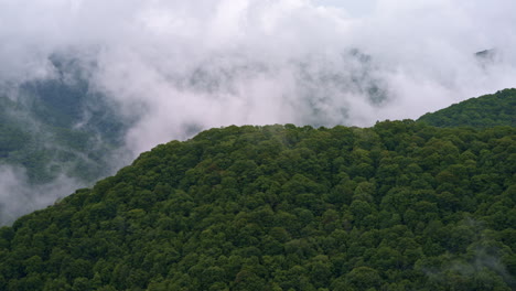 drone hovers over cloud-wrapped smoky mountain terrain