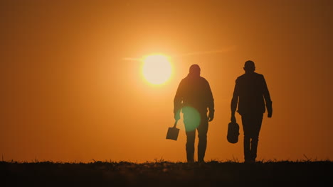 silueta de dos hombres caminando al atardecer