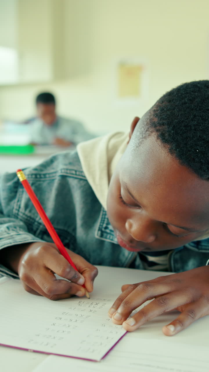 Bambino che scrive su un quaderno con una matita in un'aula