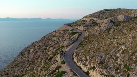 Kurvenreiche-Straße-Am-Rande-Einer-Klippe-Mit-Blick-Auf-Das-Blaue-Meer-In-Einer-Berglandschaft,-Luftdrohne