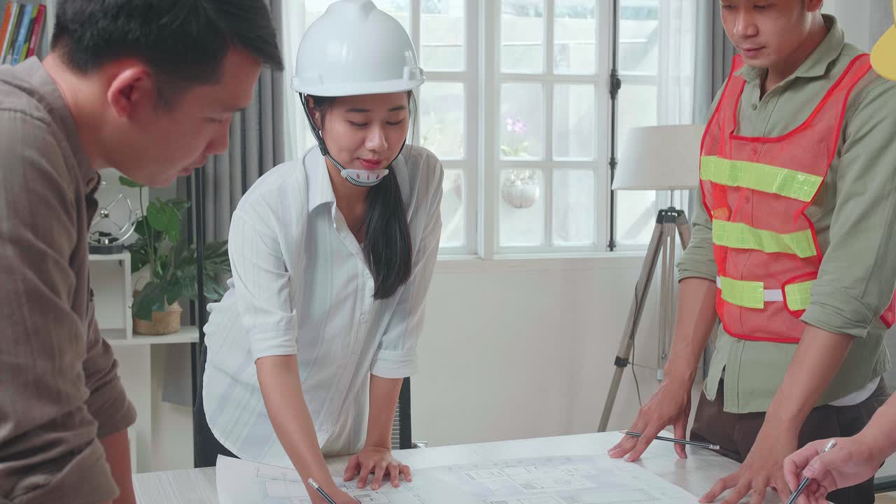 Three Asian Engineers With Helmets Presenting Work To A Man At The Office