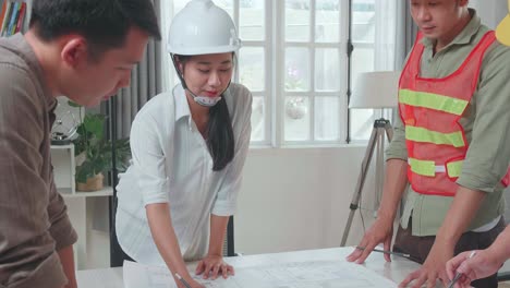three asian engineers with helmets presenting work to a man at the office