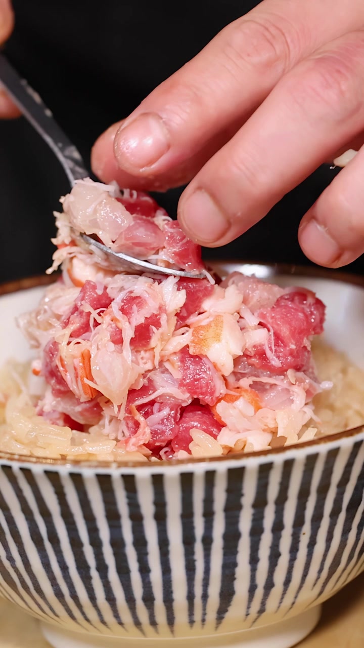 Primo piano di uno chef che impiattare meticolosamente carne di granchio fresca su una ciotola di riso.