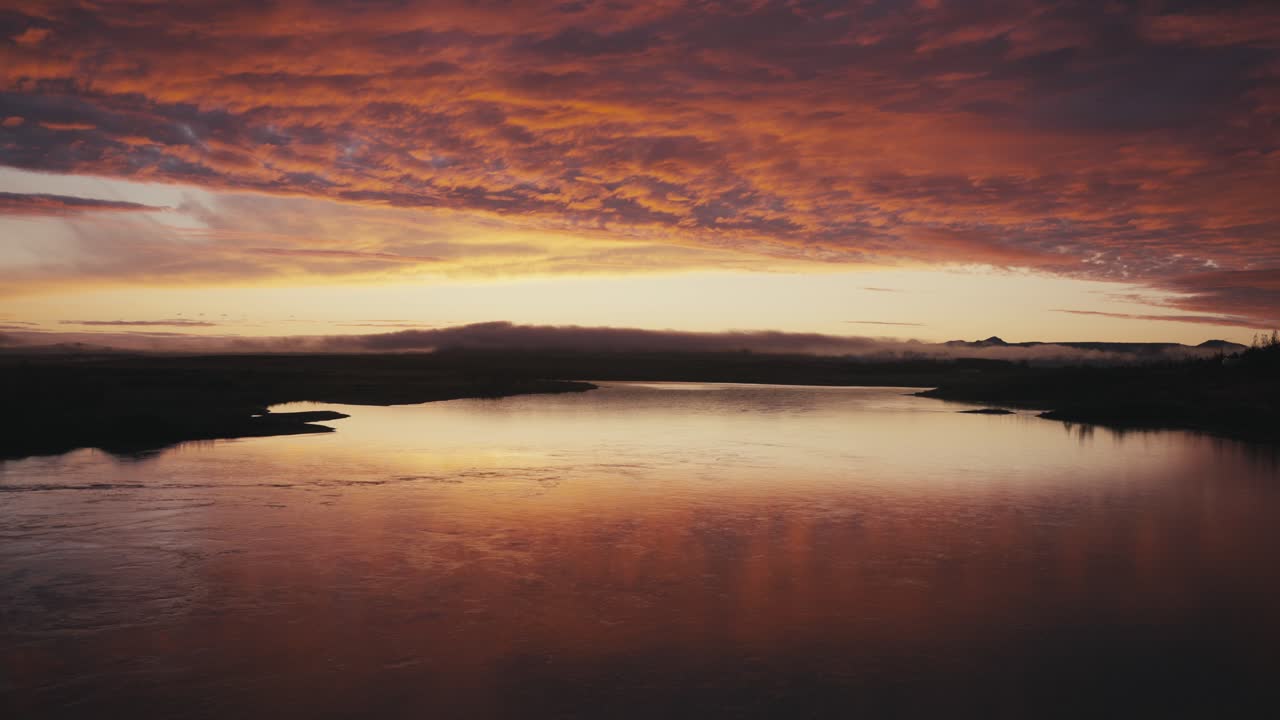 Unglaublich wunderschöne Drohnen-Luftaufnahme eines roten Sonnenuntergangs oder Sonnenaufgangs über einem Fluss.