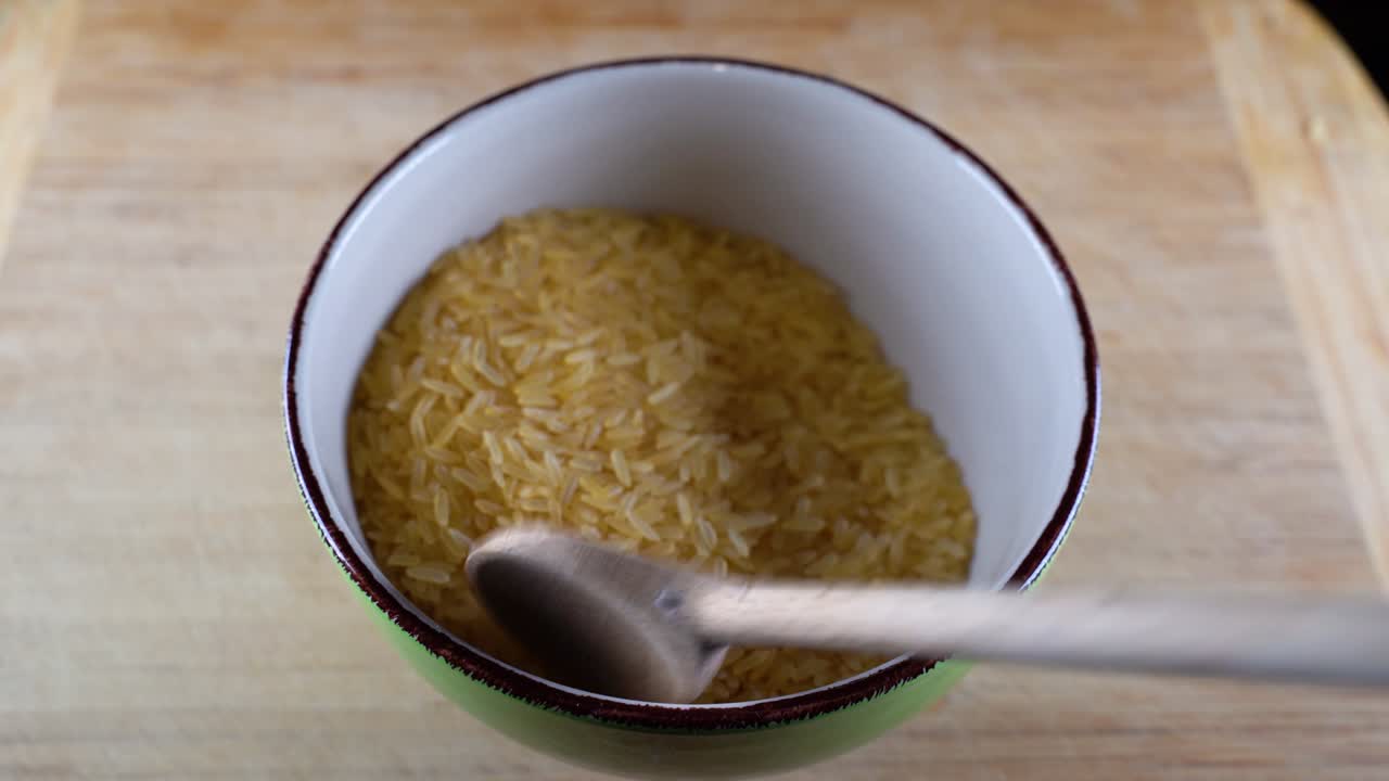 el arroz crudo se clasifica con una cuchara de madera.