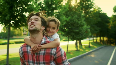 Boy-and-man-walking-on-street.-Portrait-of-joyful-father-carrying-son-on-back