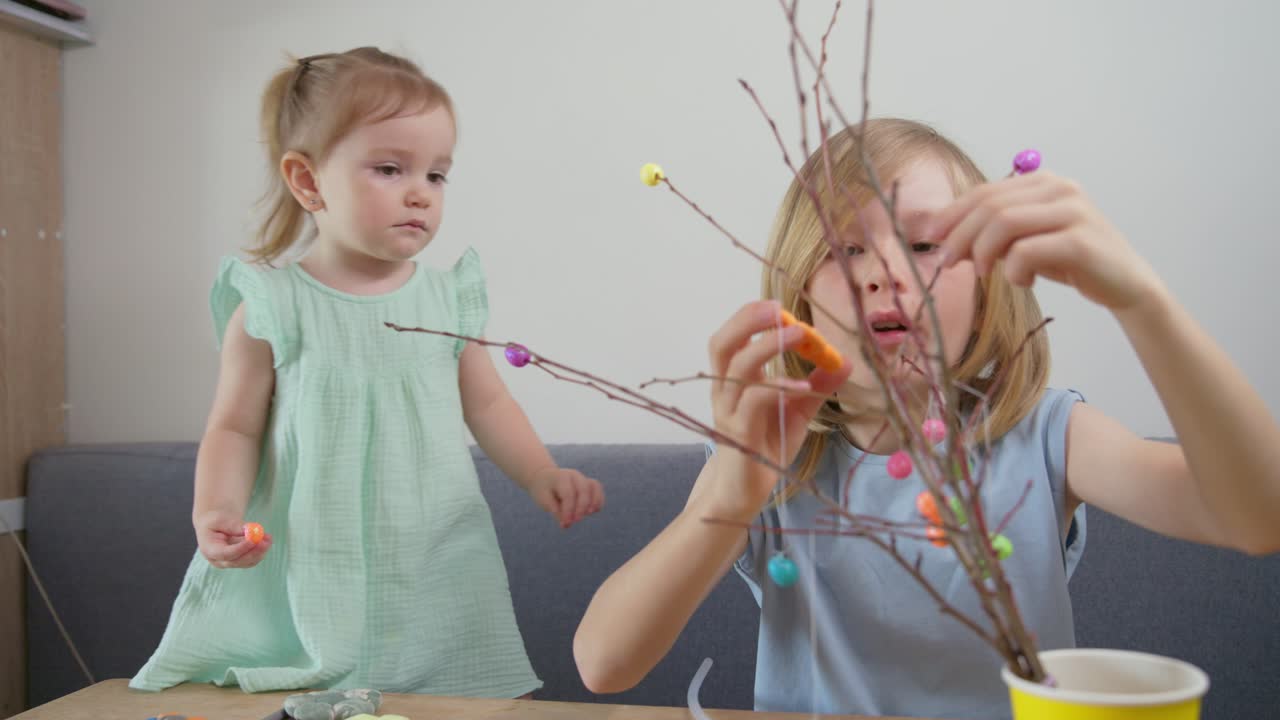 Two Young Girls Decorating Branches with Colorful Easter Ornaments