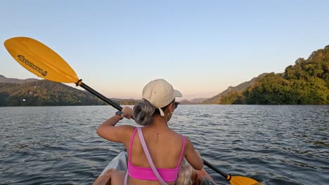 person paddling kayak on calm water at sunset