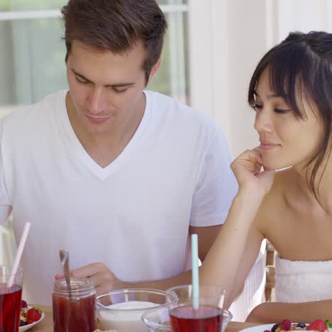 man feeding his wife fruit at breakfast