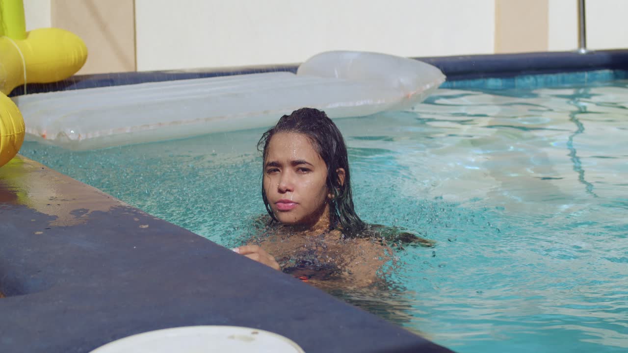chica sexy saltando en una piscina con agua de la ducha cayendo sobre ella