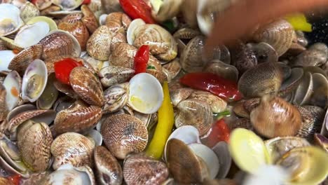 agitando deliciosas almejas frescas pimientos y tomates con tenedores de madera en sartén caliente