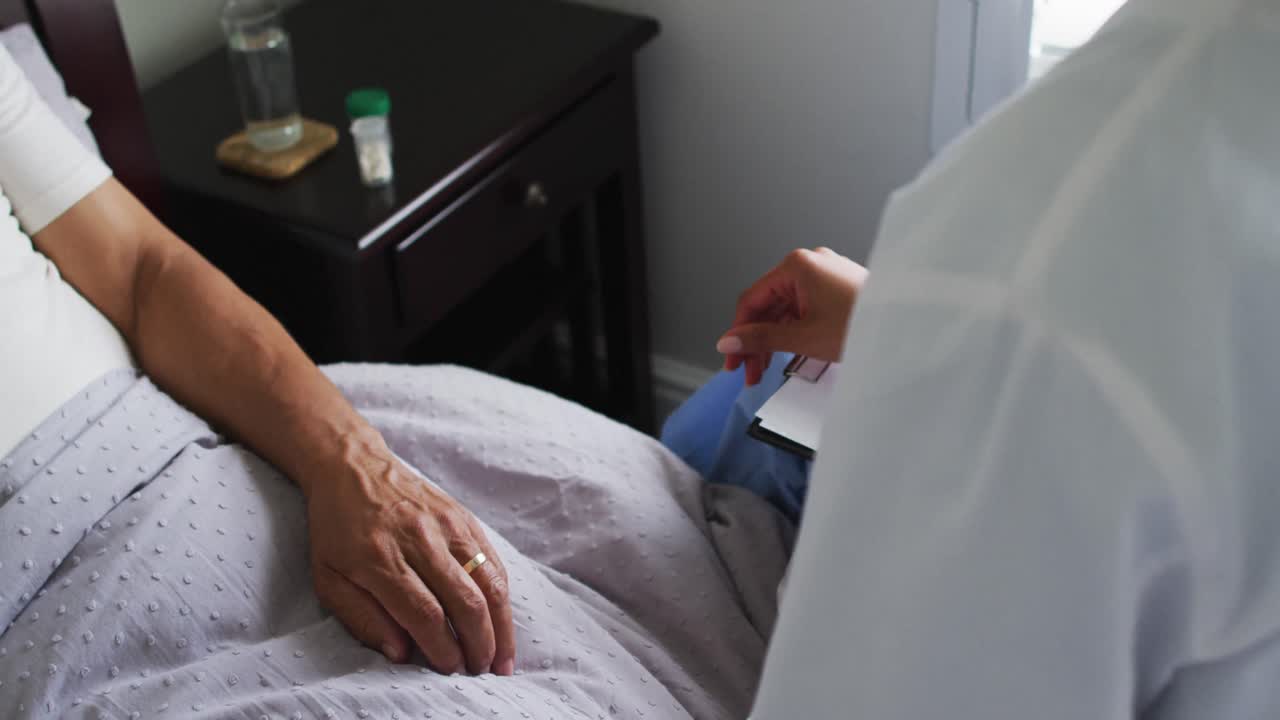Close up of senior mixed race man with female doctor home visiting holding hands