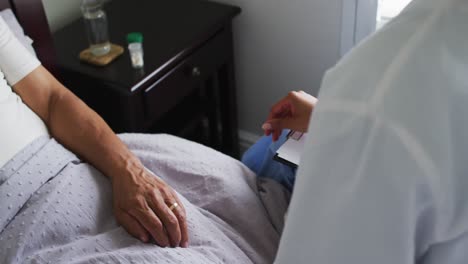 close up of senior mixed race man with female doctor home visiting holding hands