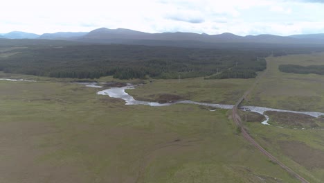 Tiro-Aéreo-Hacia-Atrás-Sobre-Rannoch-Moor-Y-La-Línea-De-Tren-Que-Lo-Atraviesa