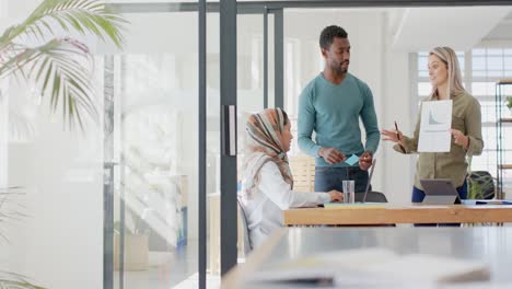 busy diverse business people discussing work at table with laptop in slow motion