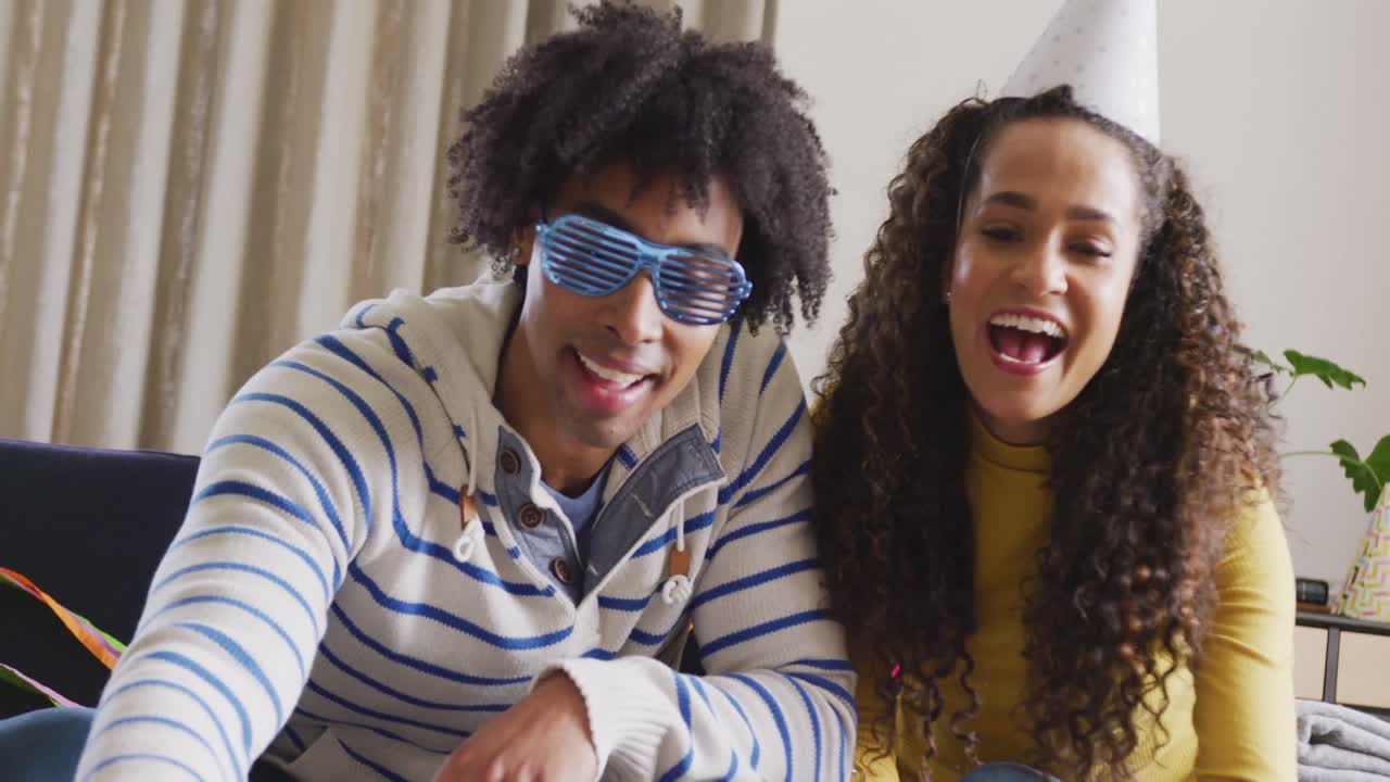 Video of happy diverse couple celebrating new years eve and making video call at home