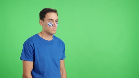 Happy man with scottish flag painted on face looking away