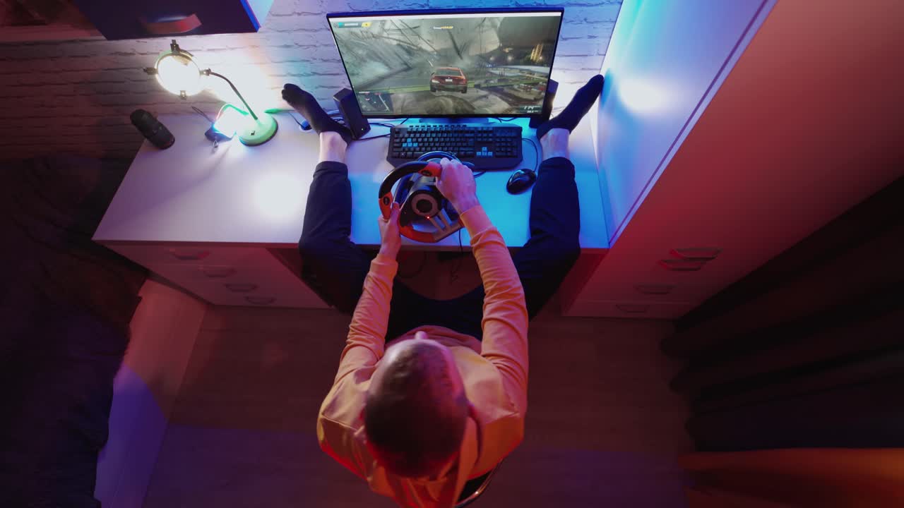 Uomo che gioca al computer a casa. Gamer maschio che si diverte con un videogioco di corse automobilistiche con volante. Concetto di gaming. Vista dall'alto