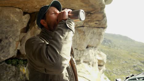 Man-drinking-water-near-a-cave-4k