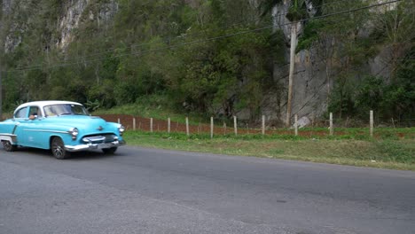 old light blue american car passing palenque