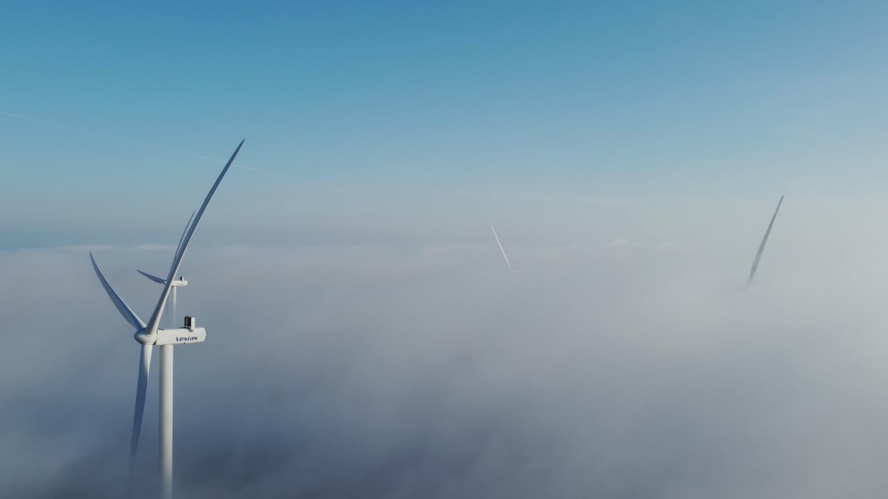 해가 뜨는 하늘 위 에 풍력 터빈 을 감싸고 있는 안개 가 많은 구름