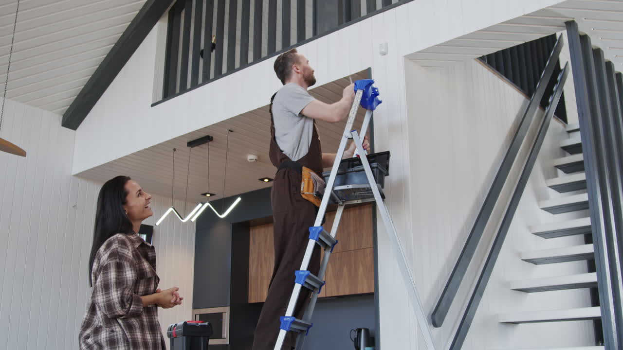 Female Homeowner Talking on Handyman Fixing Problem with Sensor