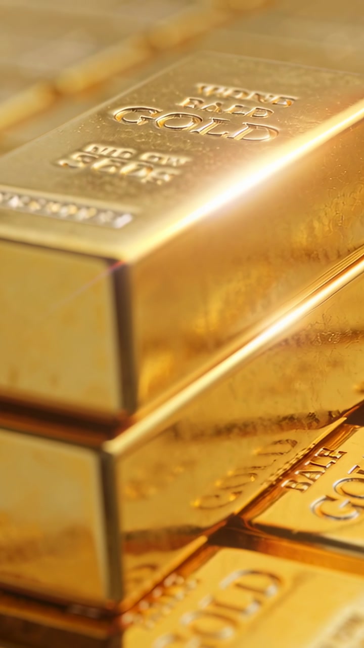 Vertical video: Moving camera revealing stamped gold bars in studio, highlighting warm reflections