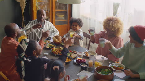 big family clinking drinks in toast at holiday dinner