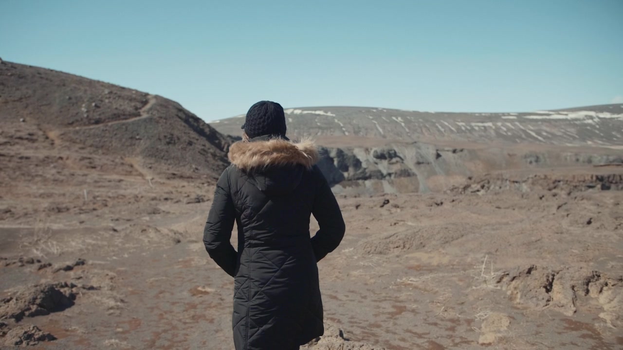 Woman in Winter Coat Looking at a Vast Rocky Landscape