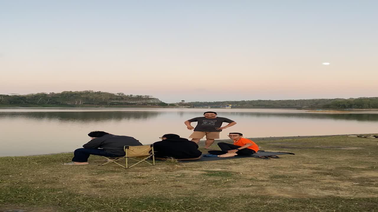 vertical timelapse footage, hanging out with friends by the lake while watching the sunset.