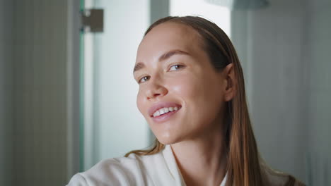 Happy girl styling hair with hot straightener closeup. Attractive lady preparing