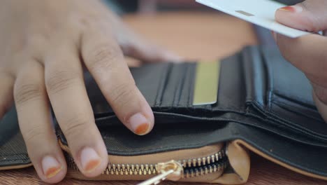 person opening a wallet containing credit card