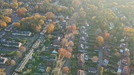 aerial of cars driving over long road through a beautiful rural town in autumn